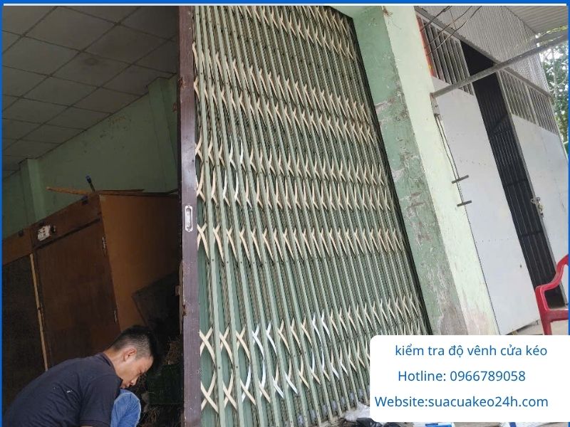 Thợ cơ khí kiểm tra độ vênh lệch của mảng cửa kéo sắt trước khi nắn