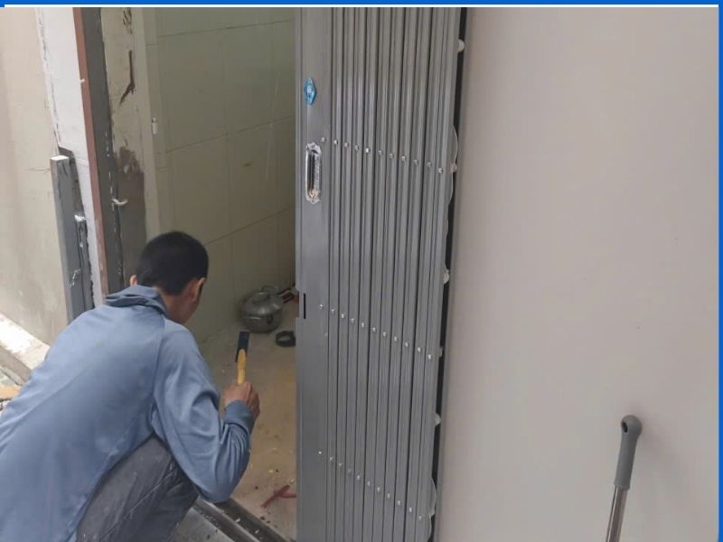 Thợ dùng búa nắn chỉnh đánh giá mức độ hư hỏng thanh ray và chân cửa kéo