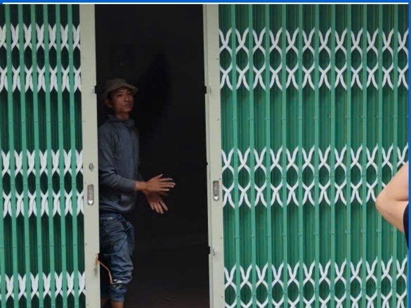 Thợ chuyên nghiệp đang dùng máy phun sơn lại cửa kéo sắt tận nhà
