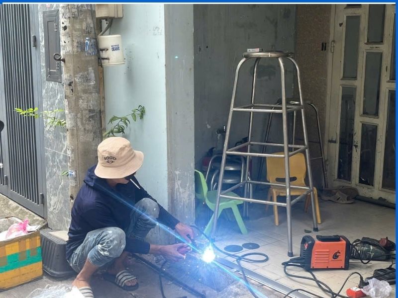 Thợ hàn cơ khí đang xử lý hàn gia cố ray cửa kéo bị bung bật khỏi nền gạch