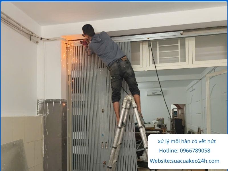 Thợ đang hàn hồ quang xử lý các vết nứt nhỏ trên khung cửa kéo sắt